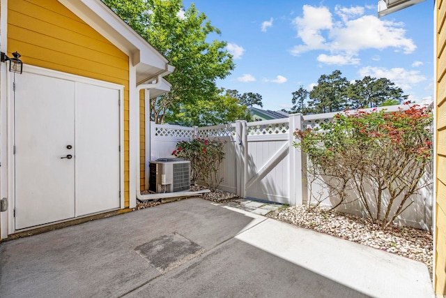 view of patio / terrace with a gate, central air condition unit, and fence