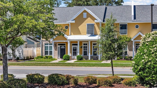view of front facade with covered porch, a front yard, brick siding, fence, and a shingled roof