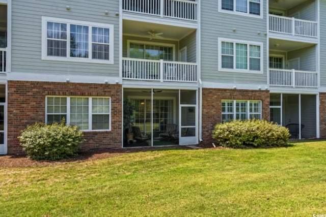 rear view of property with brick siding, a lawn, and a balcony
