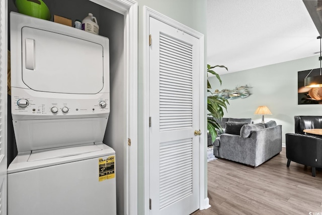 washroom with laundry area, stacked washer / dryer, and wood finished floors