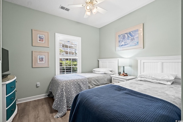 bedroom featuring visible vents, baseboards, ceiling fan, and wood finished floors