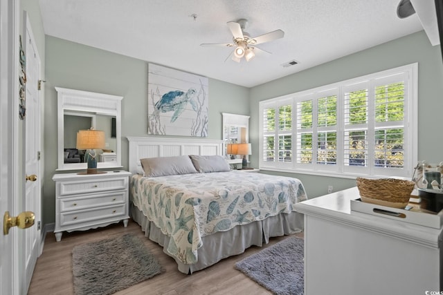 bedroom featuring ceiling fan, visible vents, and wood finished floors