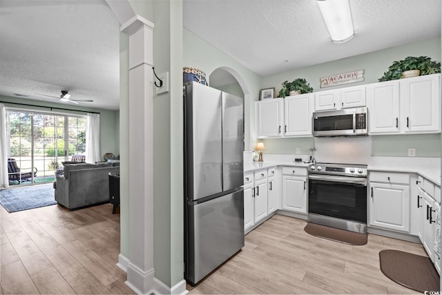 kitchen with stainless steel appliances, a textured ceiling, open floor plan, and light wood-style floors
