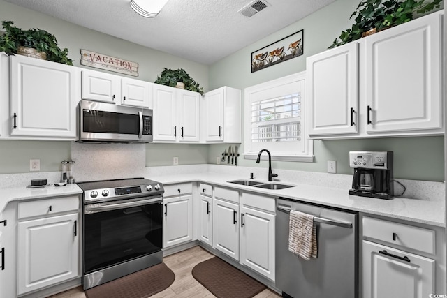 kitchen featuring a sink, light countertops, a textured ceiling, stainless steel appliances, and visible vents