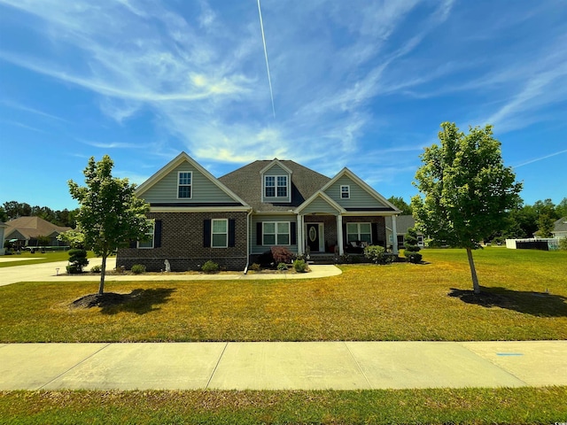 craftsman house featuring a porch, a front lawn, and brick siding