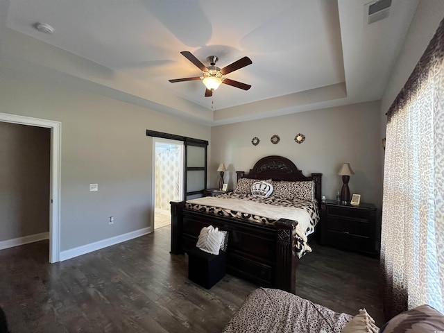 bedroom featuring dark wood-style flooring, a raised ceiling, a ceiling fan, baseboards, and visible vents