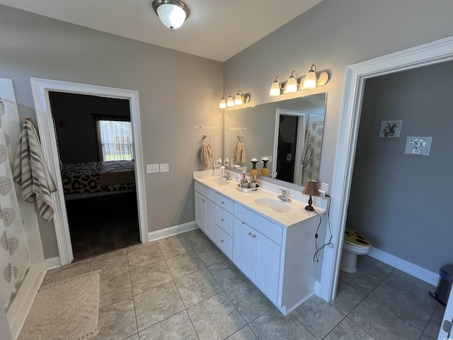ensuite bathroom featuring a sink, tile patterned floors, and double vanity
