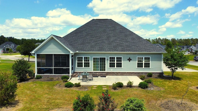 rear view of house featuring a lawn, a sunroom, a shingled roof, and a patio area