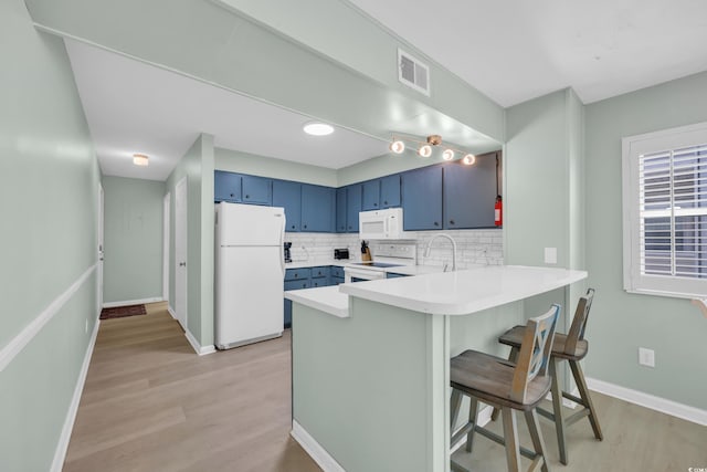 kitchen featuring white appliances, a peninsula, light wood-type flooring, visible vents, and blue cabinets