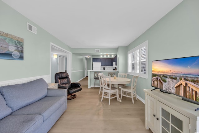 living area with baseboards, visible vents, and light wood-style flooring