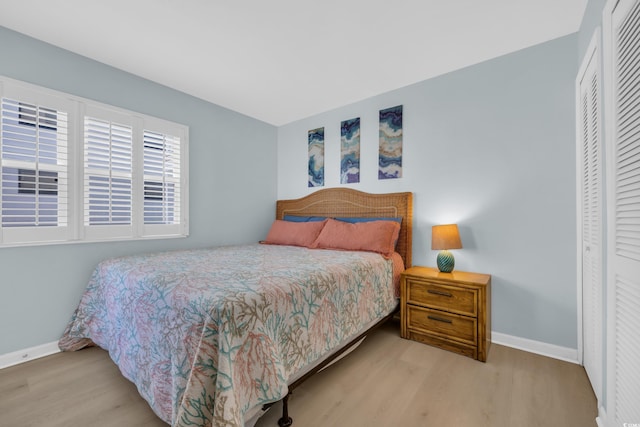 bedroom featuring baseboards, wood finished floors, and a closet