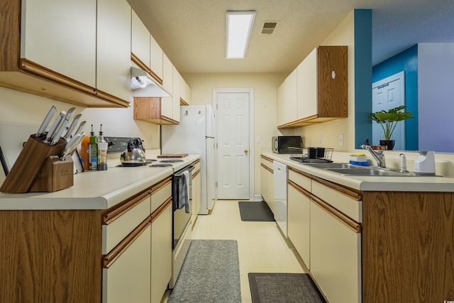 kitchen featuring visible vents, white appliances, light countertops, under cabinet range hood, and a sink