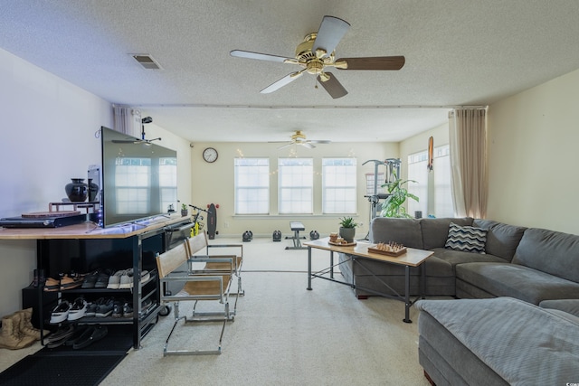 living area featuring visible vents, a textured ceiling, carpet, and ceiling fan