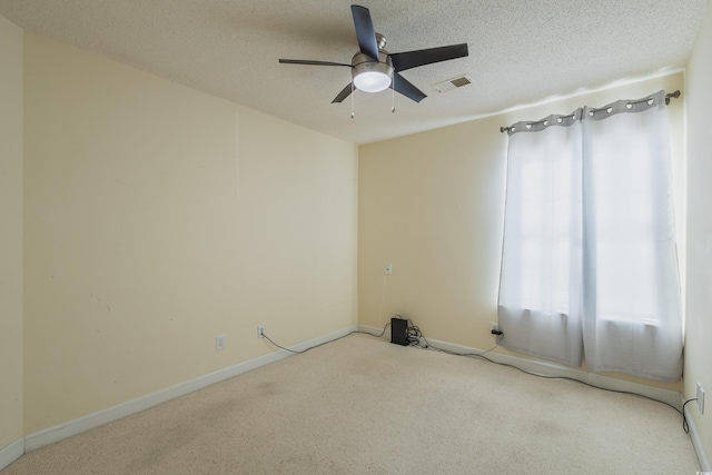 unfurnished room featuring carpet floors, ceiling fan, a textured ceiling, and visible vents