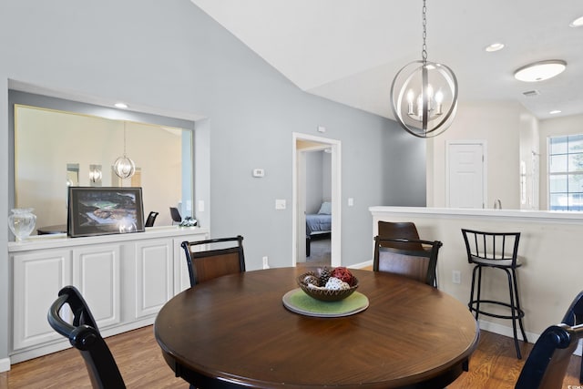 dining space featuring an inviting chandelier, lofted ceiling, light wood-style floors, baseboards, and recessed lighting