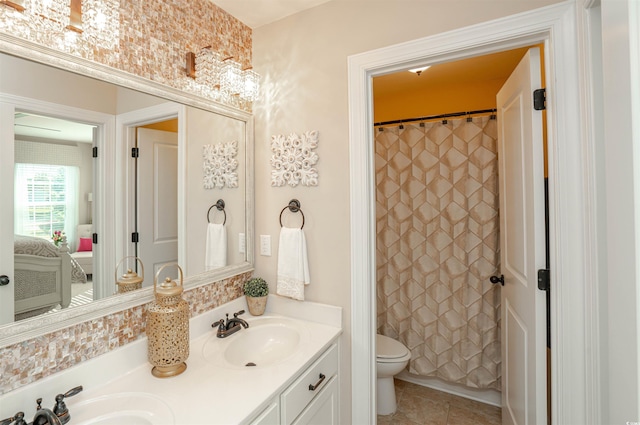 full bath featuring double vanity, a sink, tile patterned floors, and toilet