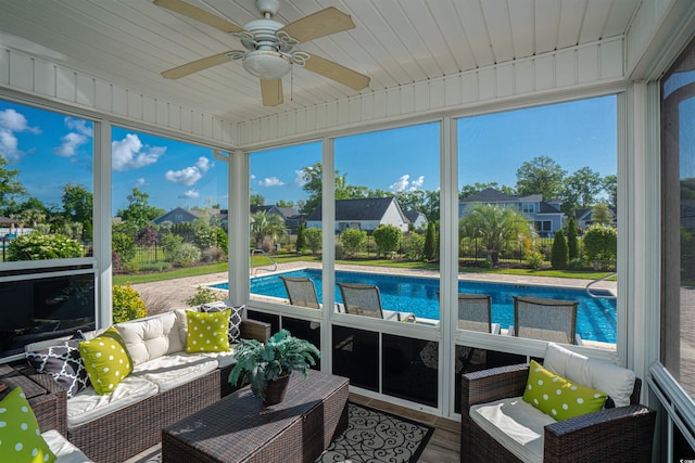 sunroom featuring ceiling fan, outdoor lounge area, and a residential view