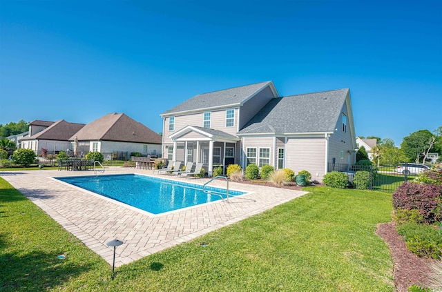 view of swimming pool featuring a lawn, a sunroom, a patio area, fence, and a fenced in pool