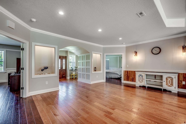 unfurnished living room with visible vents, arched walkways, a textured ceiling, and a wealth of natural light