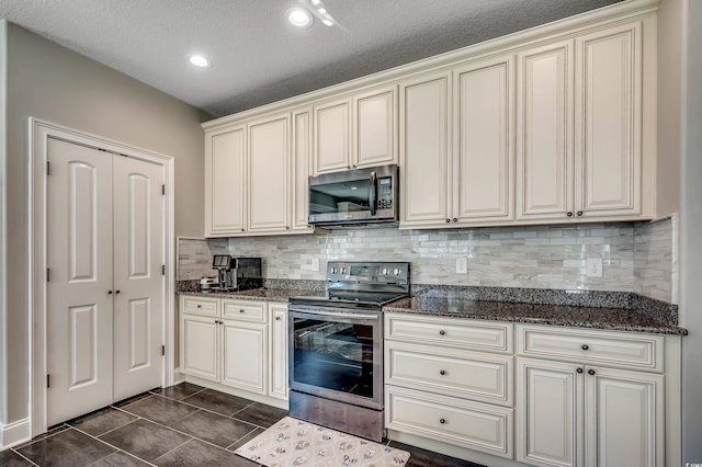 kitchen featuring dark stone counters, a textured ceiling, tasteful backsplash, and stainless steel appliances