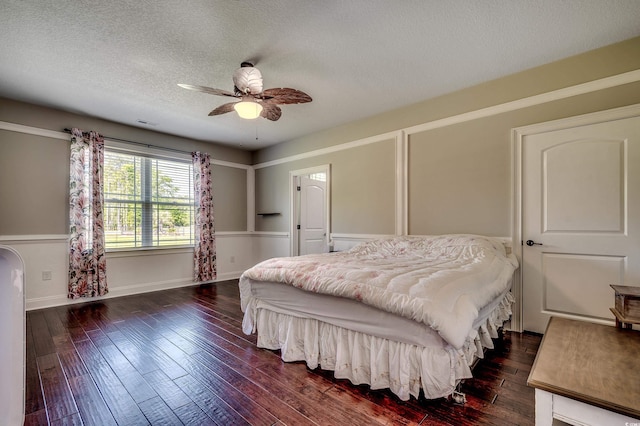 bedroom featuring dark wood-style flooring, a textured ceiling, visible vents, and ceiling fan