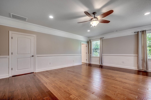 spare room with ceiling fan, visible vents, ornamental molding, and hardwood / wood-style floors