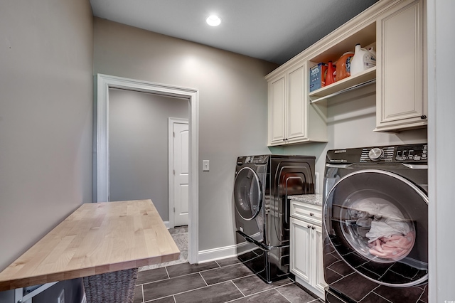 washroom with baseboards, cabinet space, washing machine and dryer, and dark tile patterned floors