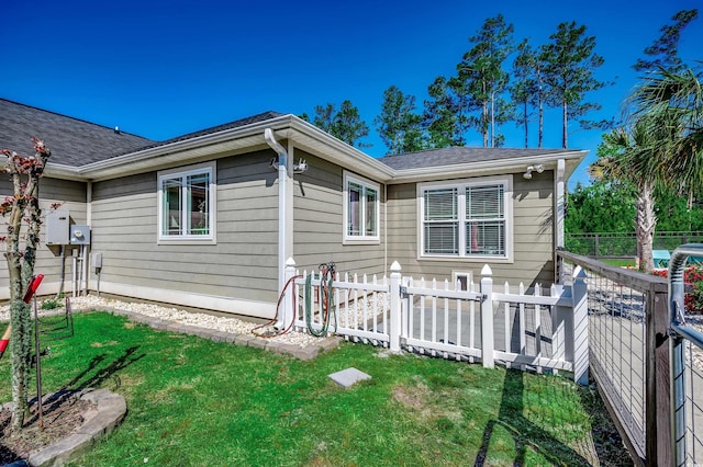 exterior space featuring a yard, fence, and roof with shingles
