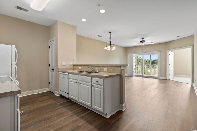kitchen with white appliances, a sink, dark wood finished floors, a peninsula, and recessed lighting