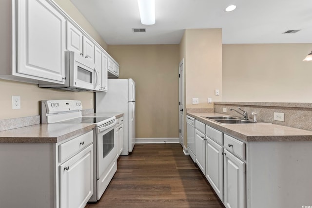 kitchen featuring white appliances, a sink, white cabinets, recessed lighting, and dark wood-style floors