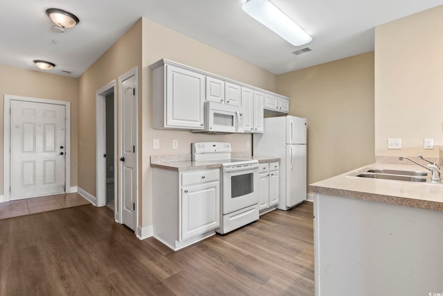 kitchen with white appliances, a sink, dark wood-style floors, light countertops, and white cabinetry
