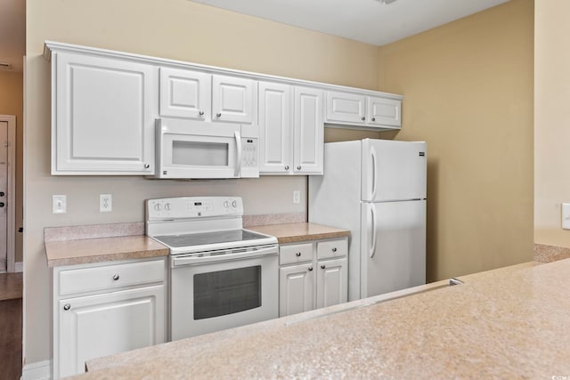kitchen with white appliances, light countertops, and white cabinetry