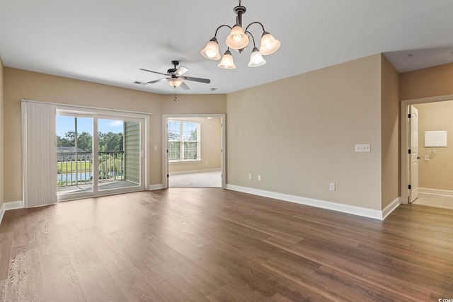 empty room with dark wood-type flooring, baseboards, ceiling fan, and a chandelier