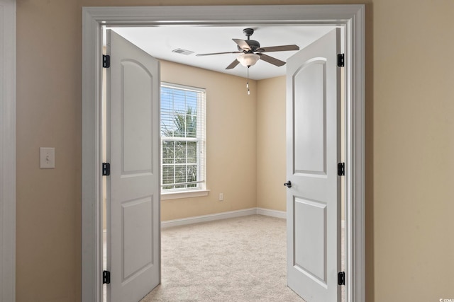 empty room with a ceiling fan, light carpet, and baseboards