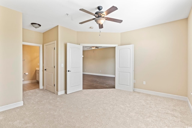 unfurnished bedroom with carpet, baseboards, ensuite bathroom, and ceiling fan