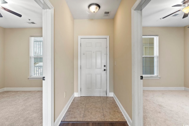 entryway with ceiling fan, carpet floors, and baseboards