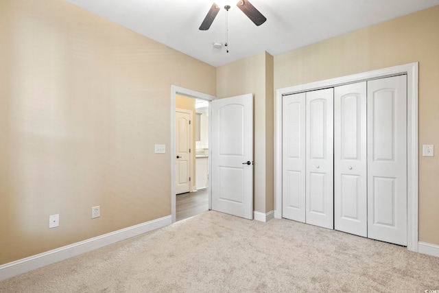 unfurnished bedroom with carpet flooring, baseboards, a closet, and a ceiling fan