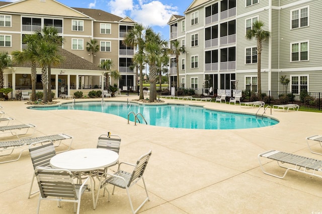 community pool with a patio and fence