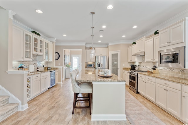 2446 Craven Dr, Myrtle Beach, SC 29572 - kitchen with backsplash, appliances with stainless steel finishes, beverage cooler, a breakfast bar, and under cabinet range hood