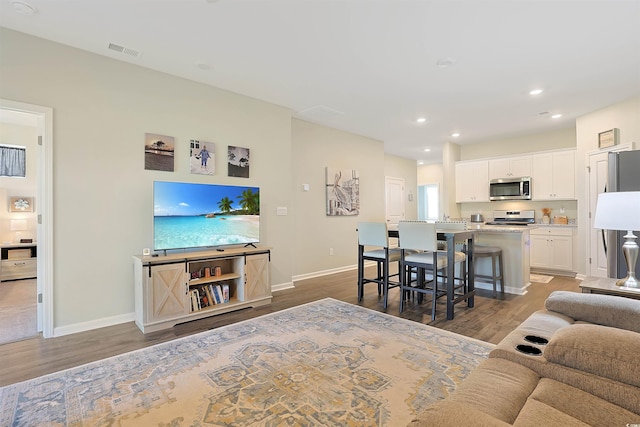 living area featuring recessed lighting, baseboards, visible vents, and wood finished floors