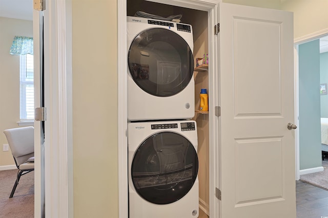 laundry room with baseboards, laundry area, and stacked washer / dryer
