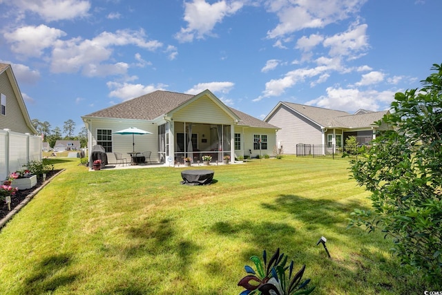 rear view of house with a lawn, a patio area, fence, and a sunroom