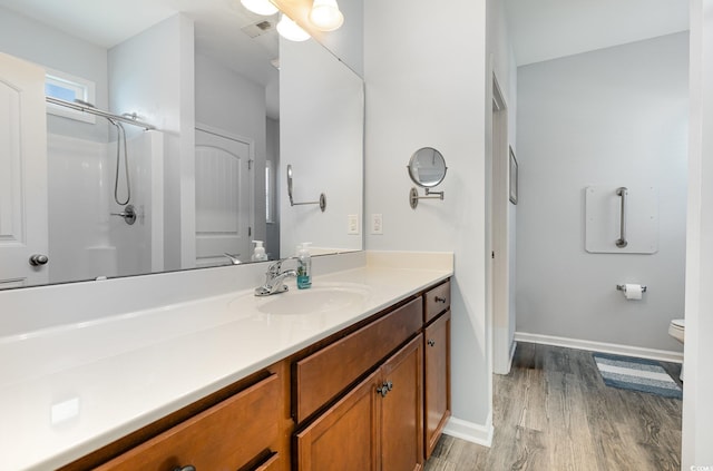 full bath featuring visible vents, wood finished floors, vanity, baseboards, and toilet