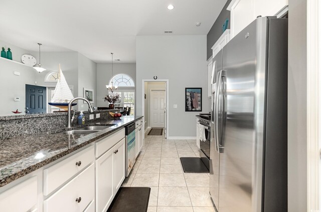 kitchen featuring hanging light fixtures, a sink, white cabinets, dark stone counters, and stainless steel appliances
