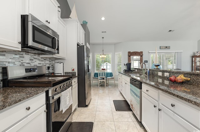 kitchen featuring decorative backsplash, appliances with stainless steel finishes, a sink, light tile patterned floors, and white cabinetry