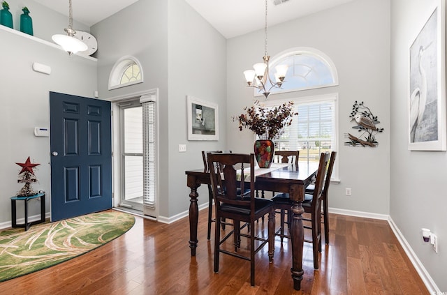 dining room with baseboards, dark wood-type flooring, and a towering ceiling