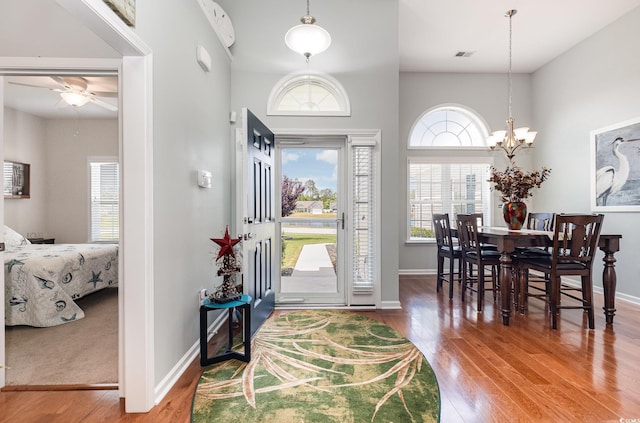 entryway with visible vents, baseboards, ceiling fan with notable chandelier, and wood finished floors