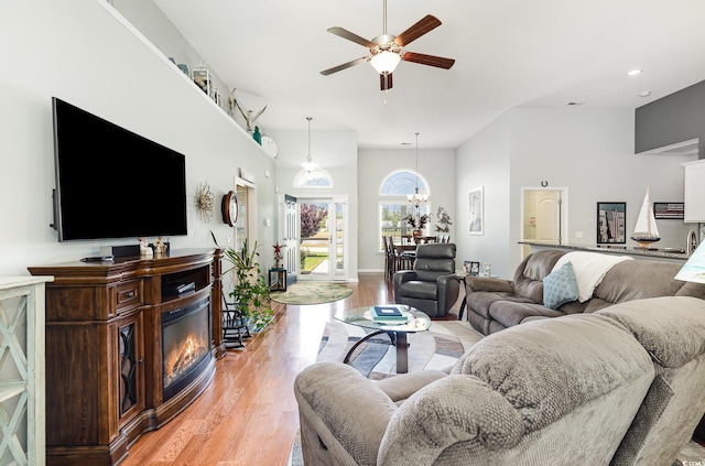 living area with ceiling fan, a glass covered fireplace, light wood-style flooring, recessed lighting, and baseboards
