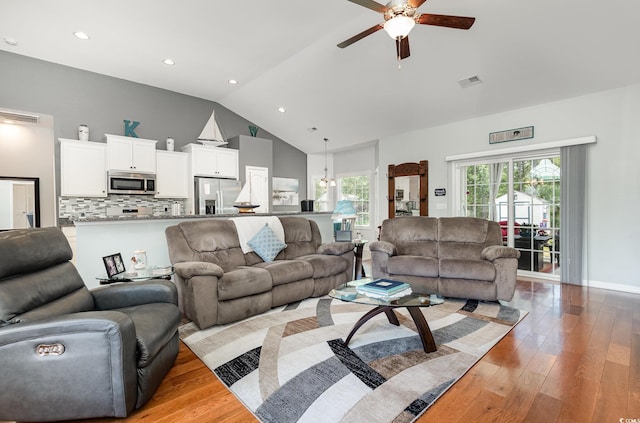 living area with a ceiling fan, visible vents, light wood finished floors, and vaulted ceiling