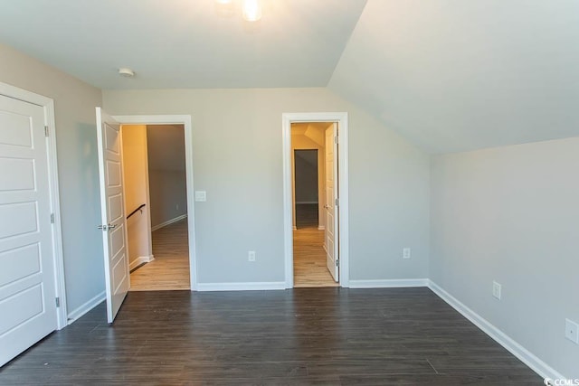unfurnished bedroom featuring baseboards, dark wood finished floors, and lofted ceiling
